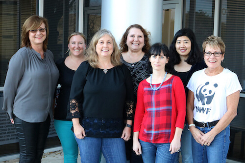 7 women stand together and smile