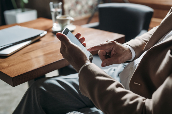 man in suit sitting at table looking at phone screen