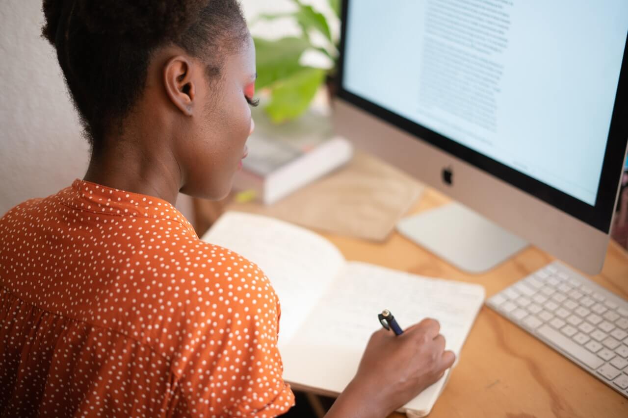 woman writing in a notebook at a desk